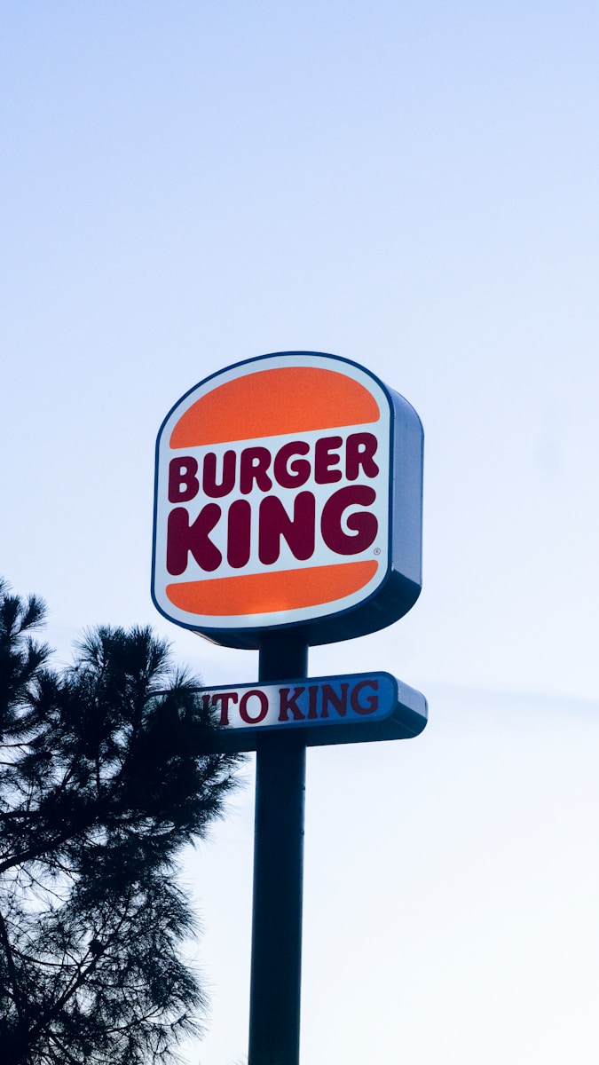 Photo by Pablo de la Fuente a burger king sign with a tree in the background