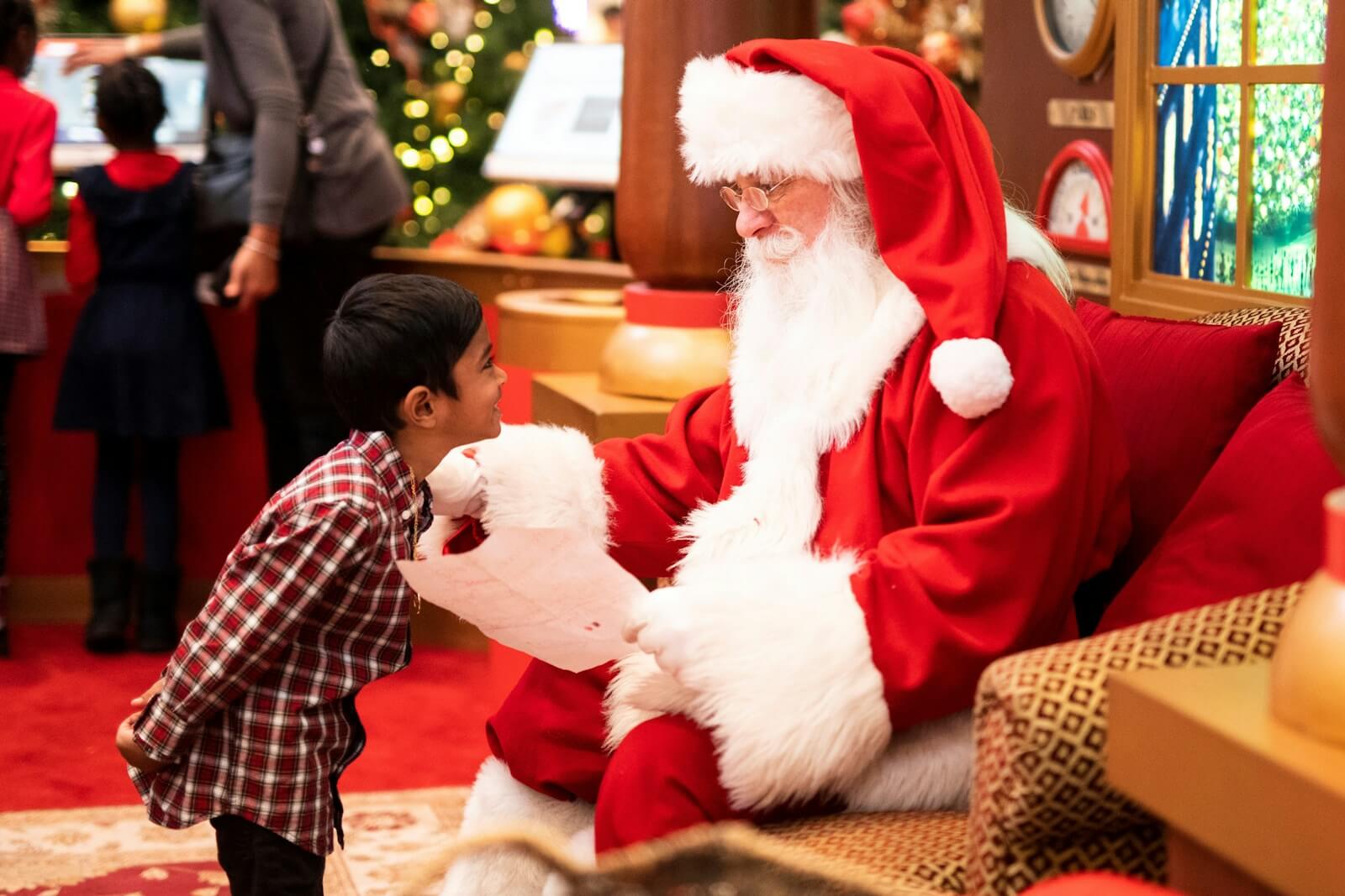 Photo by __ drz __ boy standing in front of man wearing Santa Claus costume